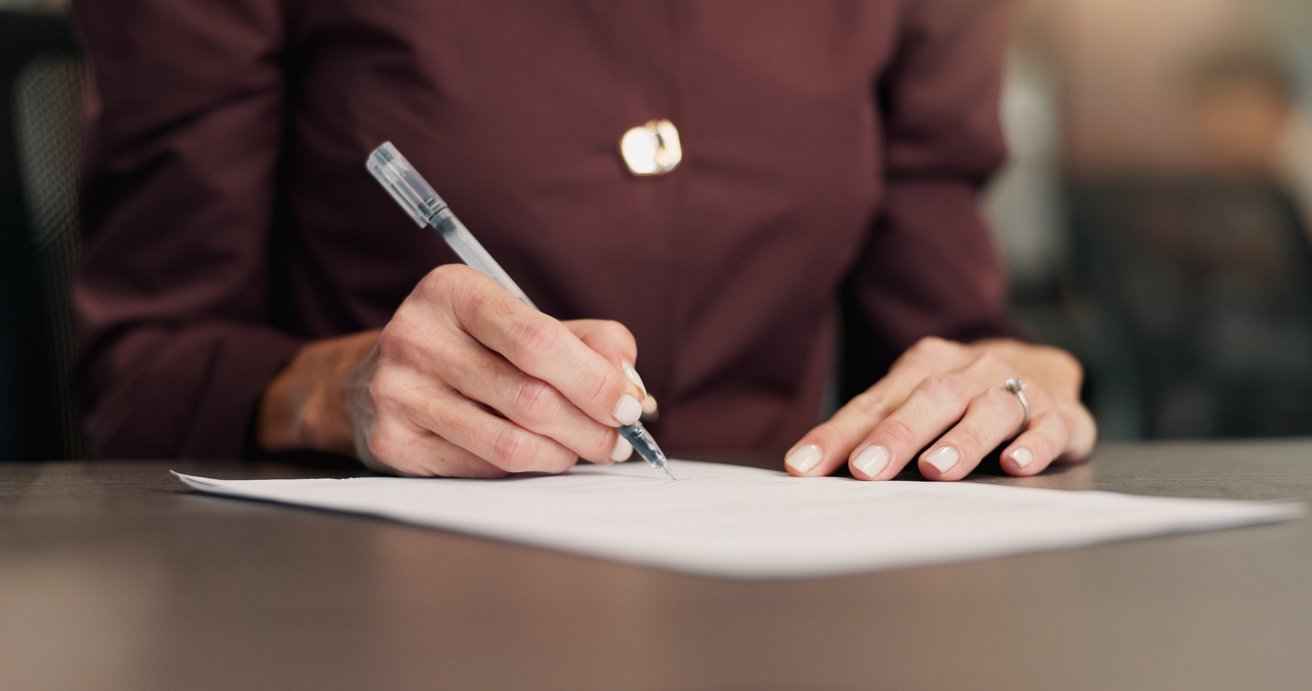 A person signing a document at a desk