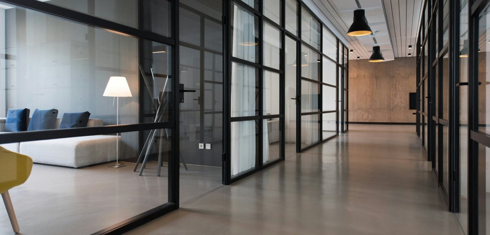 A calm office corridor lined with glass meeting rooms